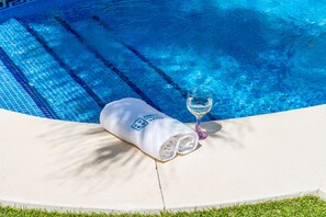 A poolside area with a towel and a glass of water.
