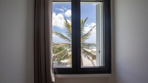 A window with a view of palm trees and a beach.