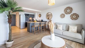 A modern living room with a sofa, a round coffee table, and a large potted plant.