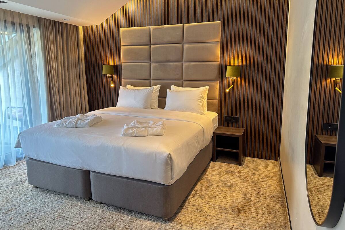 Ein modernes Hotelzimmer mit einem großen Bett, zwei Nachttischen und einem Spiegel.