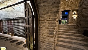 A stone staircase leading to a higher level, with a wooden door and a wall of wine bottles. - Chateau MephisKalaki (Kaspi)