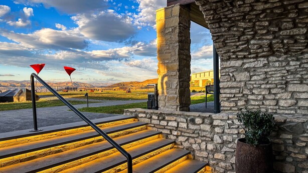 A stone staircase with metal railings and a view of a building in the background. - Chateau MephisKalaki (Kaspi)