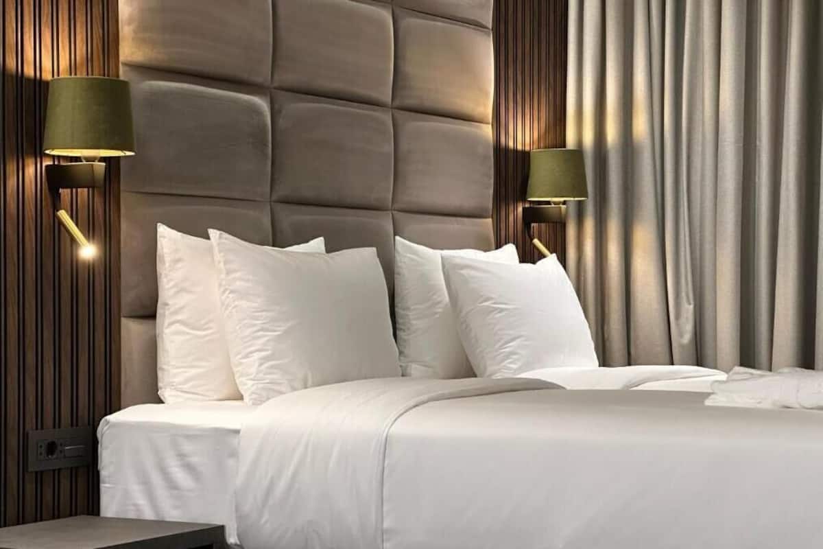 Ein modernes Schlafzimmer mit einer gesteppten Kopfteil, weißer Bettwäsche und zwei Wandleuchten.