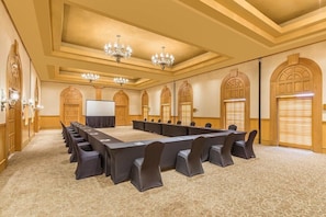 A conference room with a long table, chairs, chandeliers, and arched doorways.
