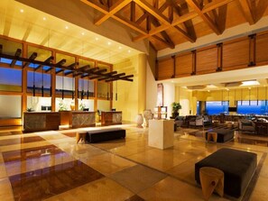 A spacious lobby with a reception desk, seating area, and a large television screen.