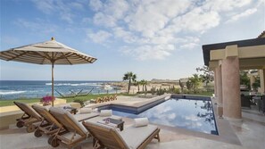 A pool area with lounge chairs and an umbrella, overlooking the ocean. - Los Cabos | Couples All-Inclusive Retreat | Pool + Beach (Cabo del Sol)
