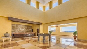 Un vestíbulo amplio con piso a cuadros, un mostrador de recepción, una pared de piedra y un gran ventanal con vistas.