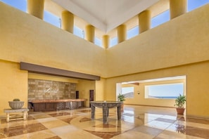 A spacious lobby with a checkered floor, a reception desk, a stone wall, and a large window offering a view.