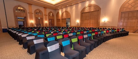 A conference room with rows of chairs, arched doorways, and a patterned carpet.