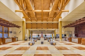 A spacious lobby with a checkered floor, wooden ceiling beams, and a central seating area.