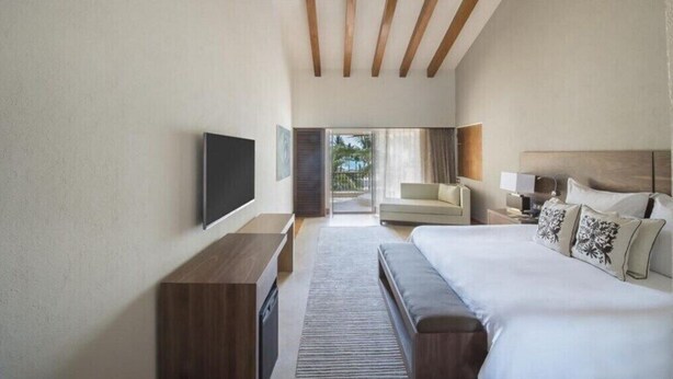 Una habitación de hotel moderna con una cama grande, un televisor de pantalla plana, un sofá y vistas al exterior.