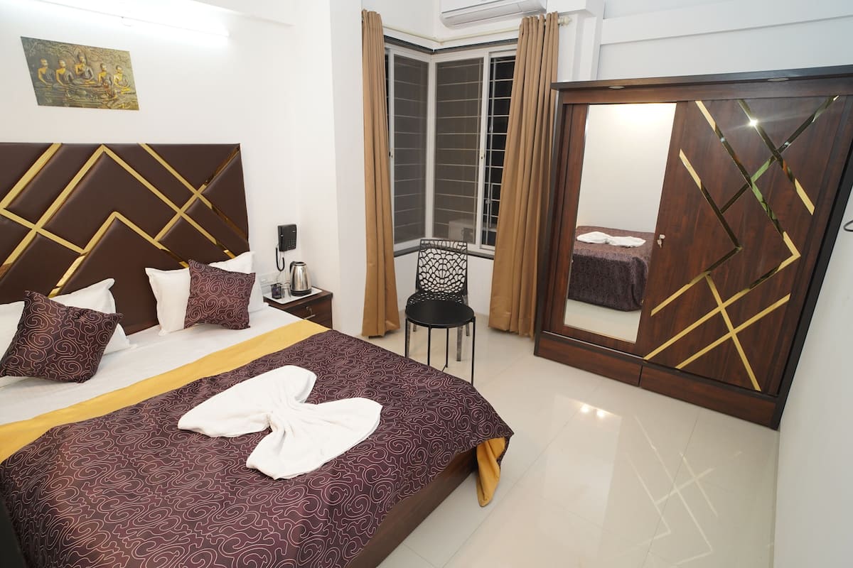 Une chambre d’hôtel avec un lit, une chaise, une armoire et une fenêtre avec des rideaux.