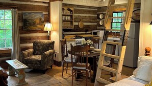 Ein rustikales Blockhaus-Interieur mit Essbereich, Holzmöbeln, einer Leiter und einem Bett.
