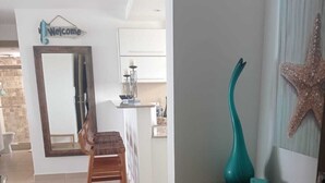 Un interior moderno con un banco de madera, un jarrón decorativo color turquesa y una decoración de estrella de mar en la pared.