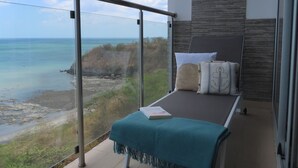 Un balcón con cama, vista al océano y diseño interior moderno.