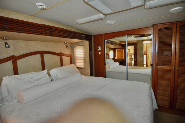A hotel room with a large bed, wooden headboard, and a mirror.