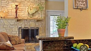 A living room with a stone fireplace, a sofa, and a potted plant.