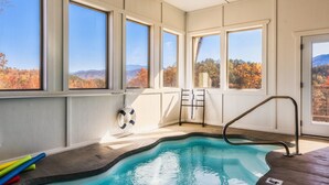 An indoor swimming pool with clear views of autumn foliage and mountains through large windows. - Fall Mtn Escape! HeatedPool-HotTub-Theater-Views (Sevierville)