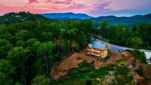 A lodge with a large open deck, surrounded by dense forest and mountains. - Fall Mtn Escape! HeatedPool-HotTub-Theater-Views (Sevierville)