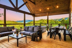 Um deck externo com piso de madeira, um sofá, uma mesa e cadeiras.