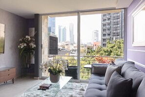 A modern living room with a grey sofa, a glass coffee table, and a potted orchid plant.