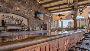 Un bar con pared de piedra, mostrador de madera y luces colgantes.