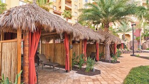 Un resort con cabañas de techo de paja, palmeras y sillas de descanso.