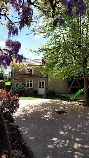 A stone house with a green slide and a gravel driveway.