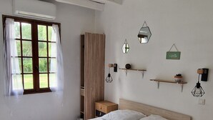 Un dormitori amb un llit gran, un armari de fusta, taules de nit i una finestra amb cortines.