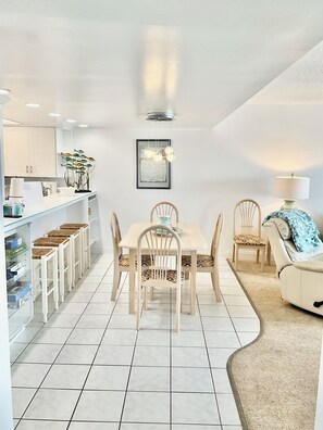 Una cocina moderna con armarios blancos, una mesa de comedor con sillas y una pequeña isla con taburetes.
