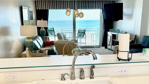 Una cocina con un lavamanos doble, armarios blancos y vistas al balcón.