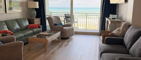 Un salon avec vue sur la plage, un téléviseur à écran plat et un canapé.