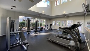 A spacious gym with various exercise equipment, large windows, and a ceiling fan. - Gorgeous Lakeview Resort Style Condo (Phoenix)