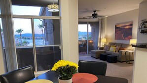 A dining area with a table set for two, a potted plant with yellow flowers, and a view of a balcony with a dining table and chairs. - Gorgeous Lakeview Resort Style Condo (Phoenix)