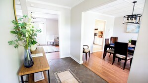 A spacious living area with a wooden coffee table, a vase with flowers, and a dining area with chairs and a table.