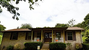 A two-story house with a front porch, a staircase leading to the entrance, and a well-maintained lawn.