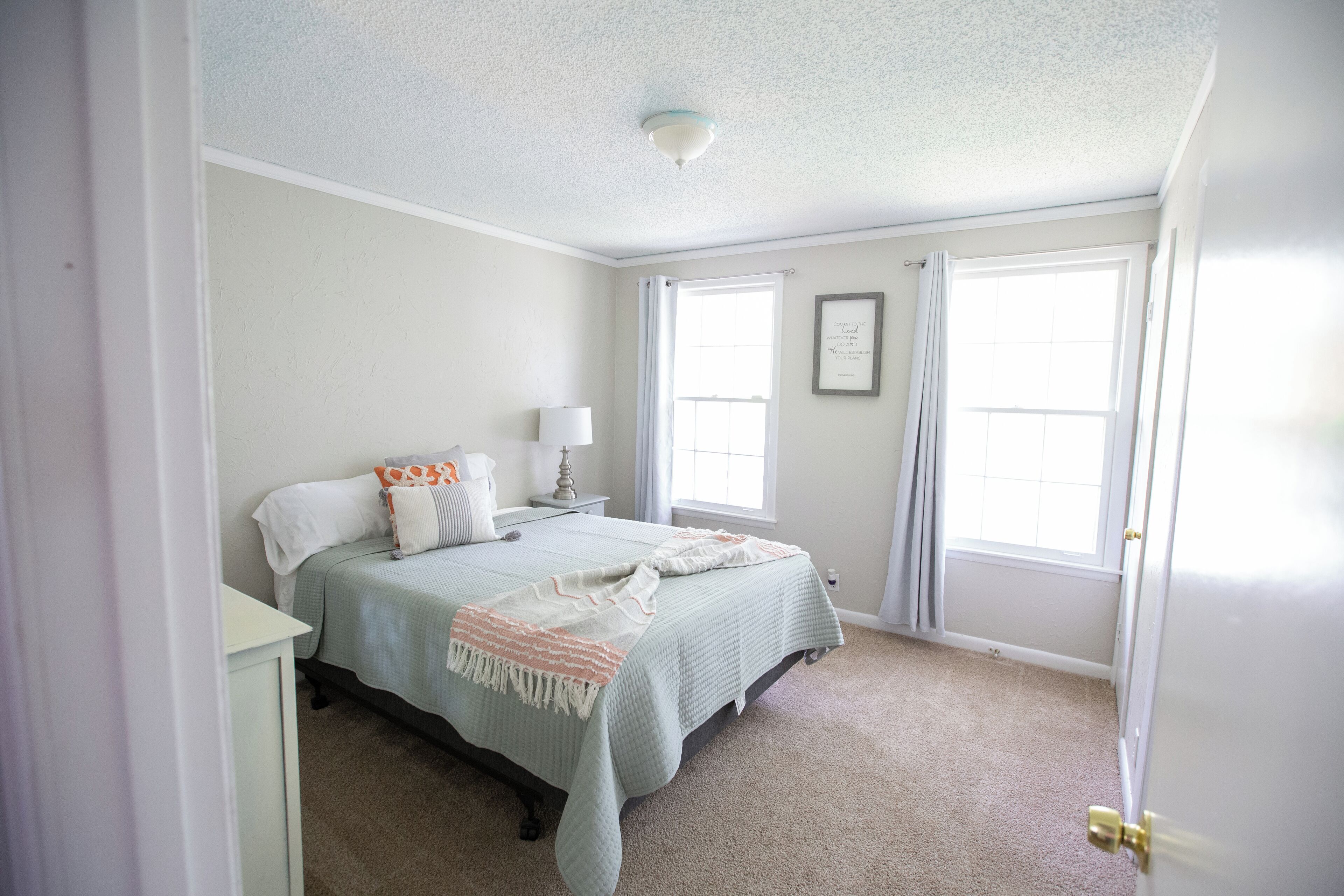 A bedroom with a bed, nightstand, and a window with curtains.