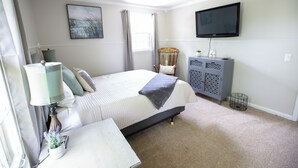 A bedroom with a bed, a bedside table, a lamp, a chair, a TV, and a cabinet.