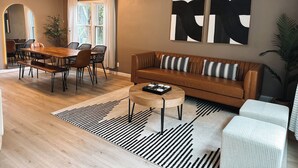 Una sala moderna con una mesa de comedor de madera, un sofá de cuero y arte abstracto en la pared.