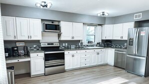 Una cocina moderna con armarios blancos, electrodomésticos de acero inoxidable y piso de madera.
