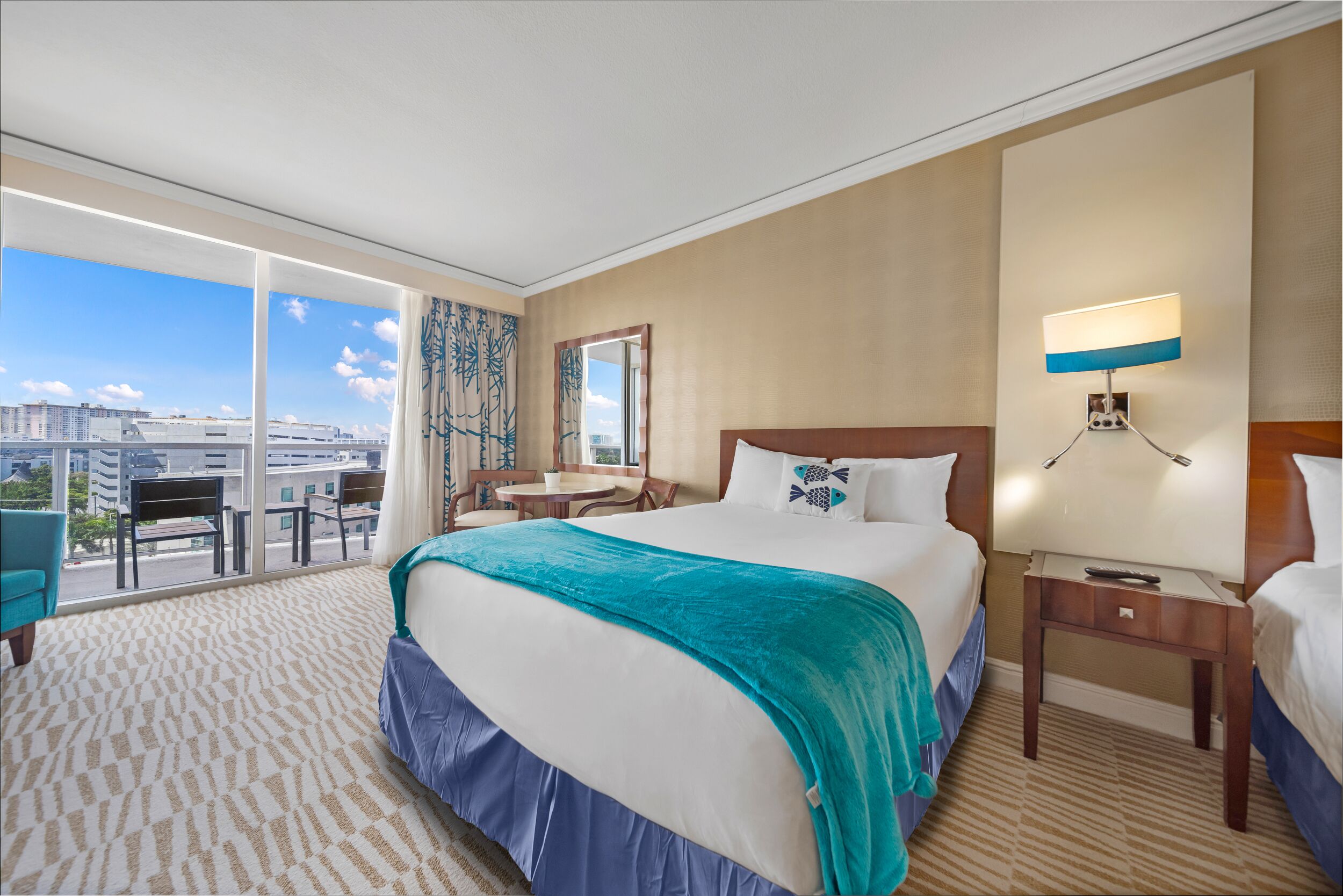 Habitación de hotel con una cama grande, un escritorio, una silla y vista a la ciudad.