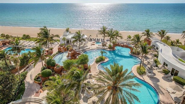 A resort with multiple swimming pools, palm trees, and a beach view.
