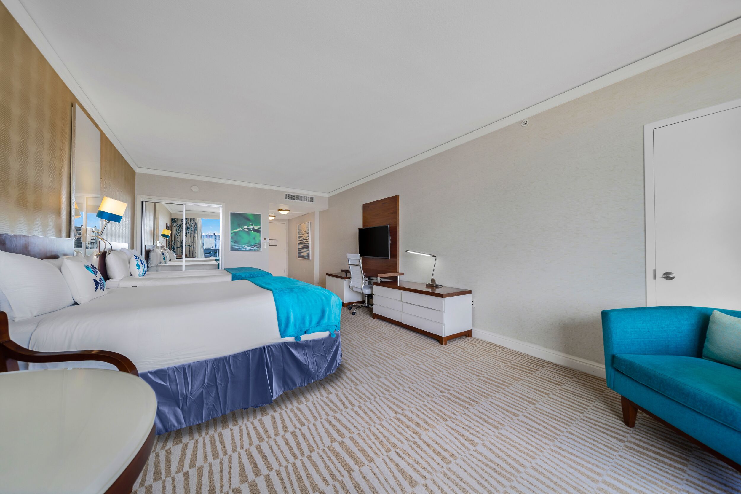 Habitación de hotel con una cama grande, un escritorio con computadora, un televisor y un sofá.