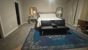 Un dormitorio con una cama, una mesita de noche, un escritorio, una silla y una alfombra azul.