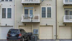 Un edificio residencial de varios pisos con un garaje y un coche estacionado frente a él.