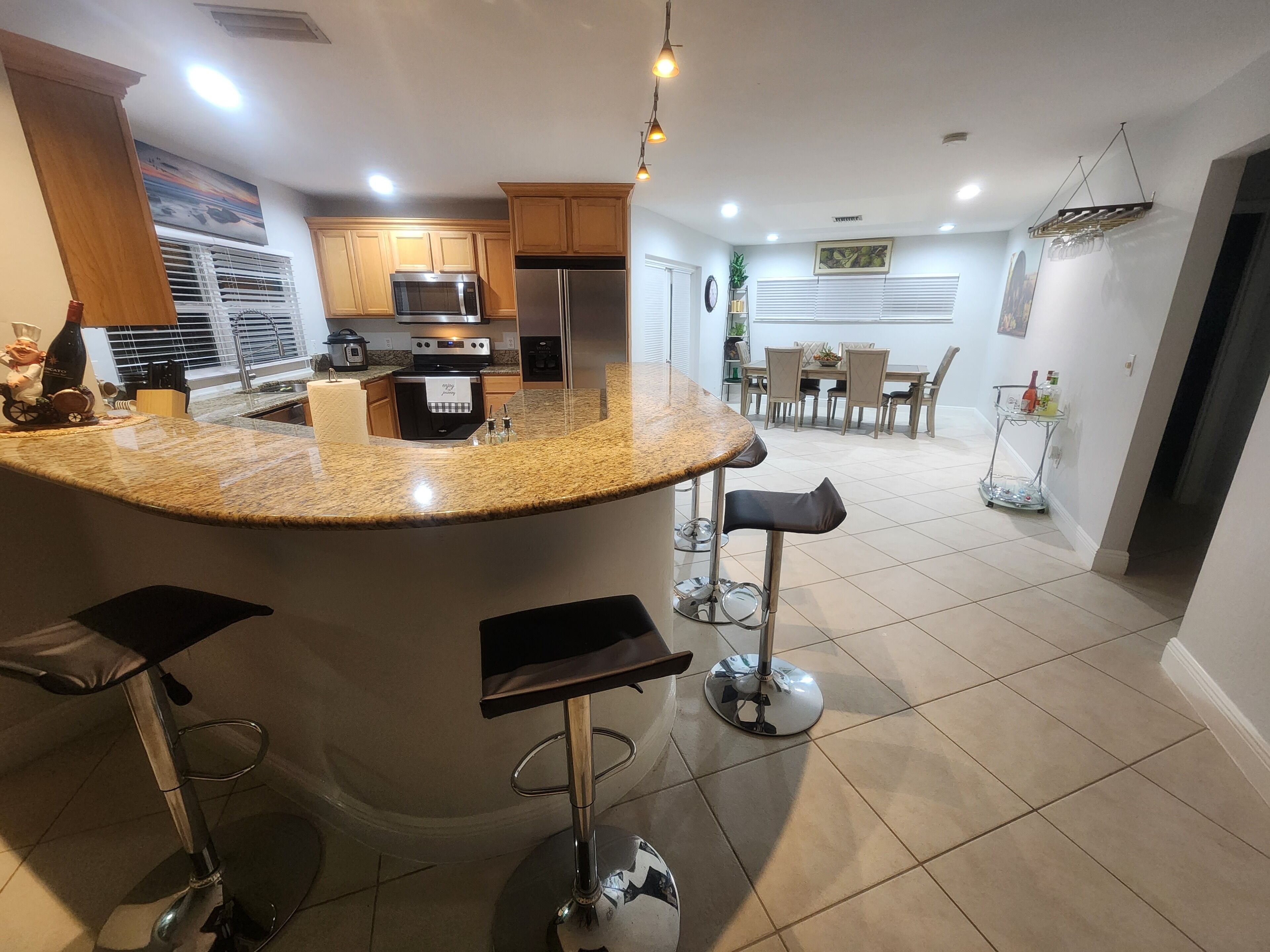 Una cocina moderna con encimeras de granito, electrodomésticos de acero inoxidable y una isla central con taburetes de bar.