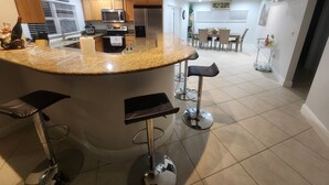 A modern kitchen with granite countertops, stainless steel appliances, and a central island with bar stools.