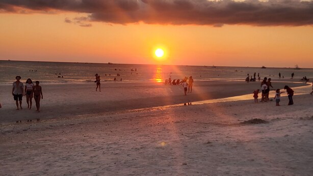 A beach scene with people walking and relaxing.