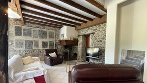 A cozy living room with a stone fireplace, a leather sofa, a white sofa, and a TV. - CHEZ CAZALETS - SUSMIOU (SUSMIOU)