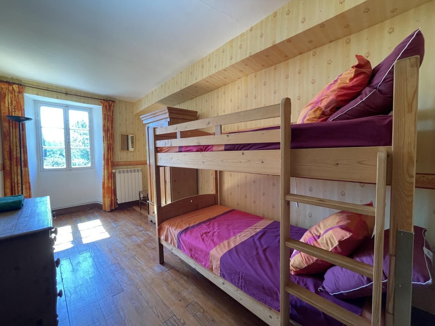 Habitación con literas, paredes de madera, una ventana y una mesita.